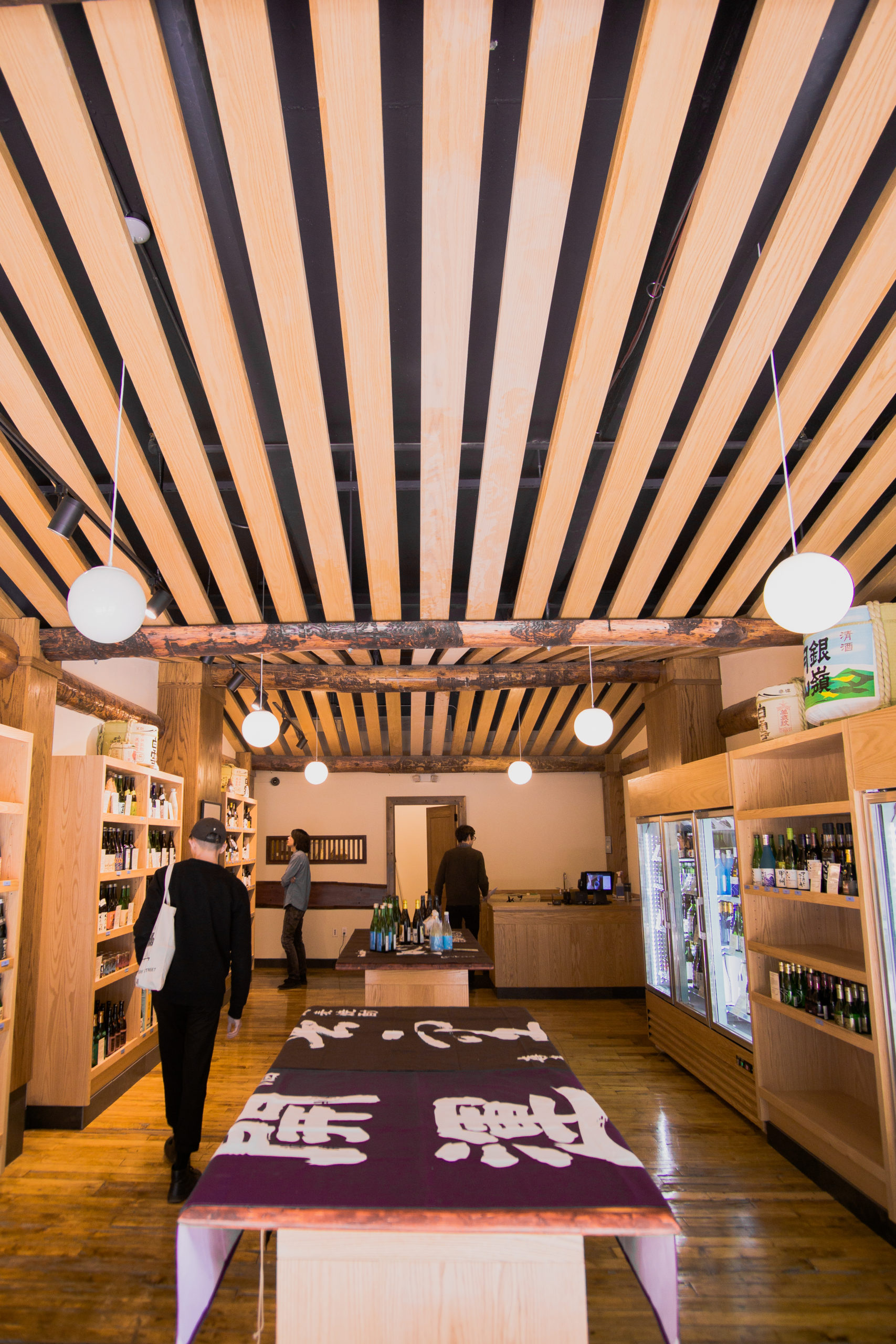 The interior of a shop with wood panels on the ceiling. People browse.