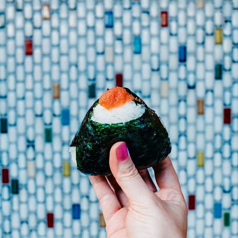 A hand holds up a piece of onigiri.
