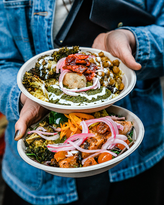 A person holds two bowls of food.