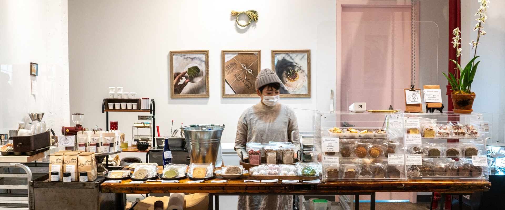 A person stands behind a counter with a display of baked goods