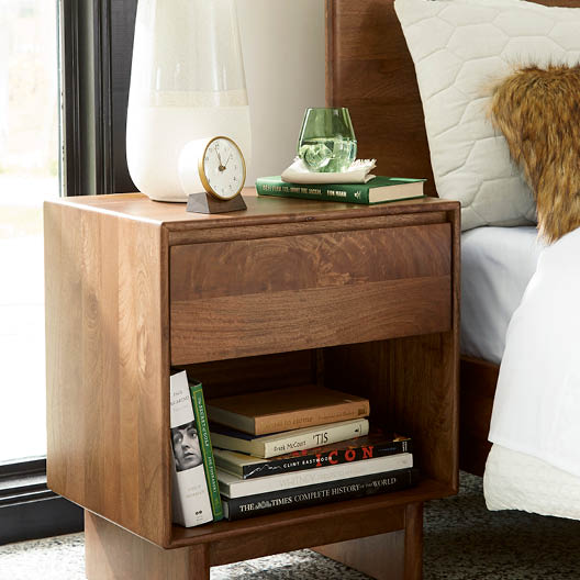There is a bedside table with books on it.