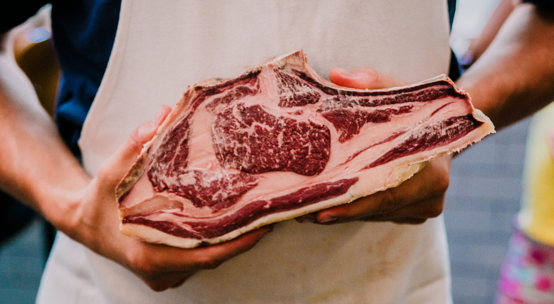 A butcher is holding a large piece of raw meat.