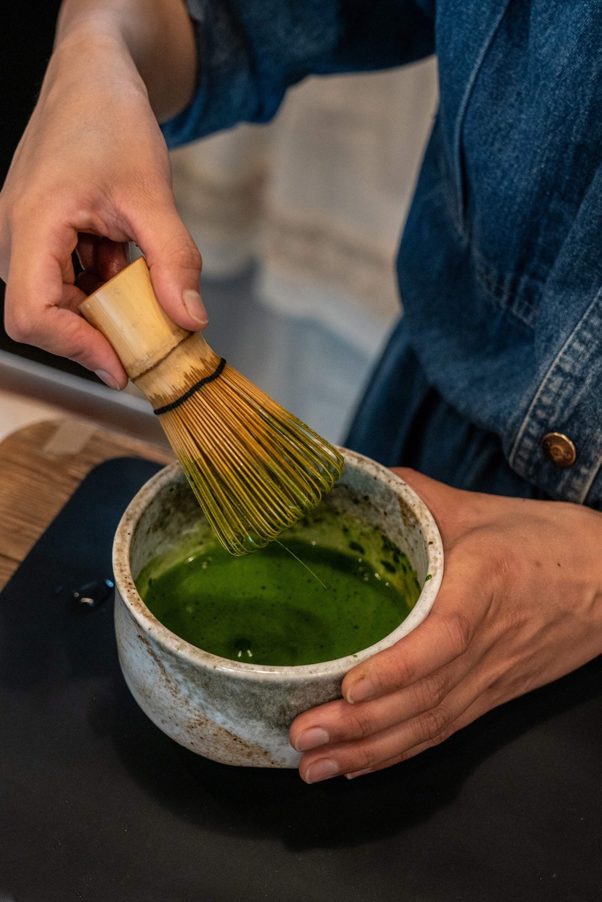 Someone is mixing matcha in a small dish.