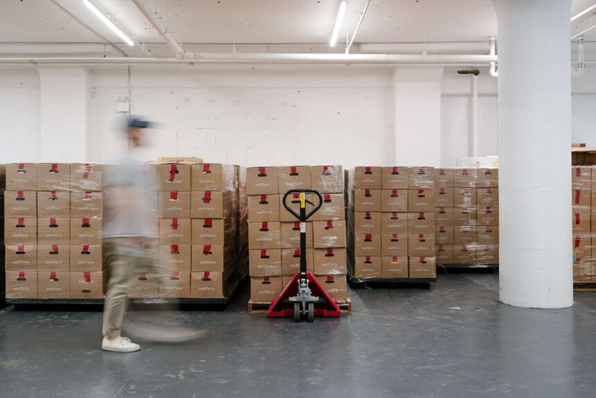 There are boxes in a warehouse with someone standing in front of them.