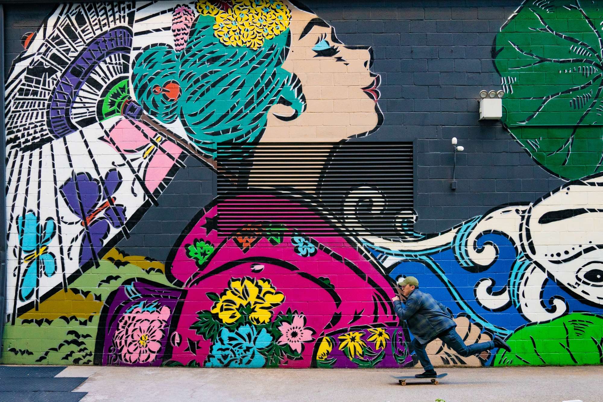 Someone is skating boarding by an outdoor mural.