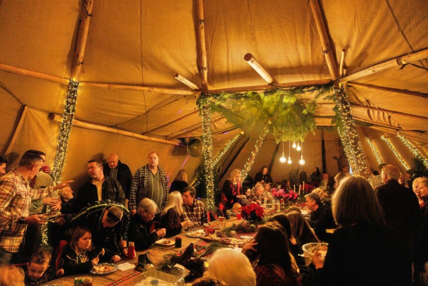 A tent event space with people sitting around eating dinner and talking.