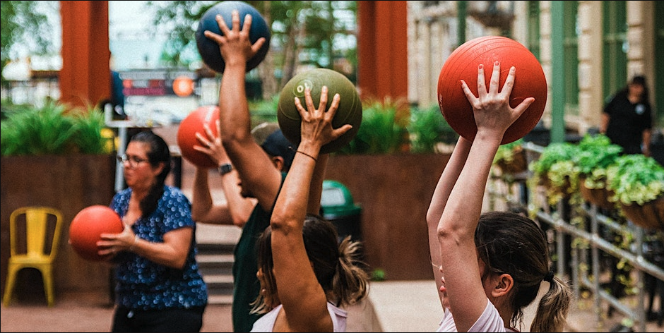 People raise workout balls over their heads.